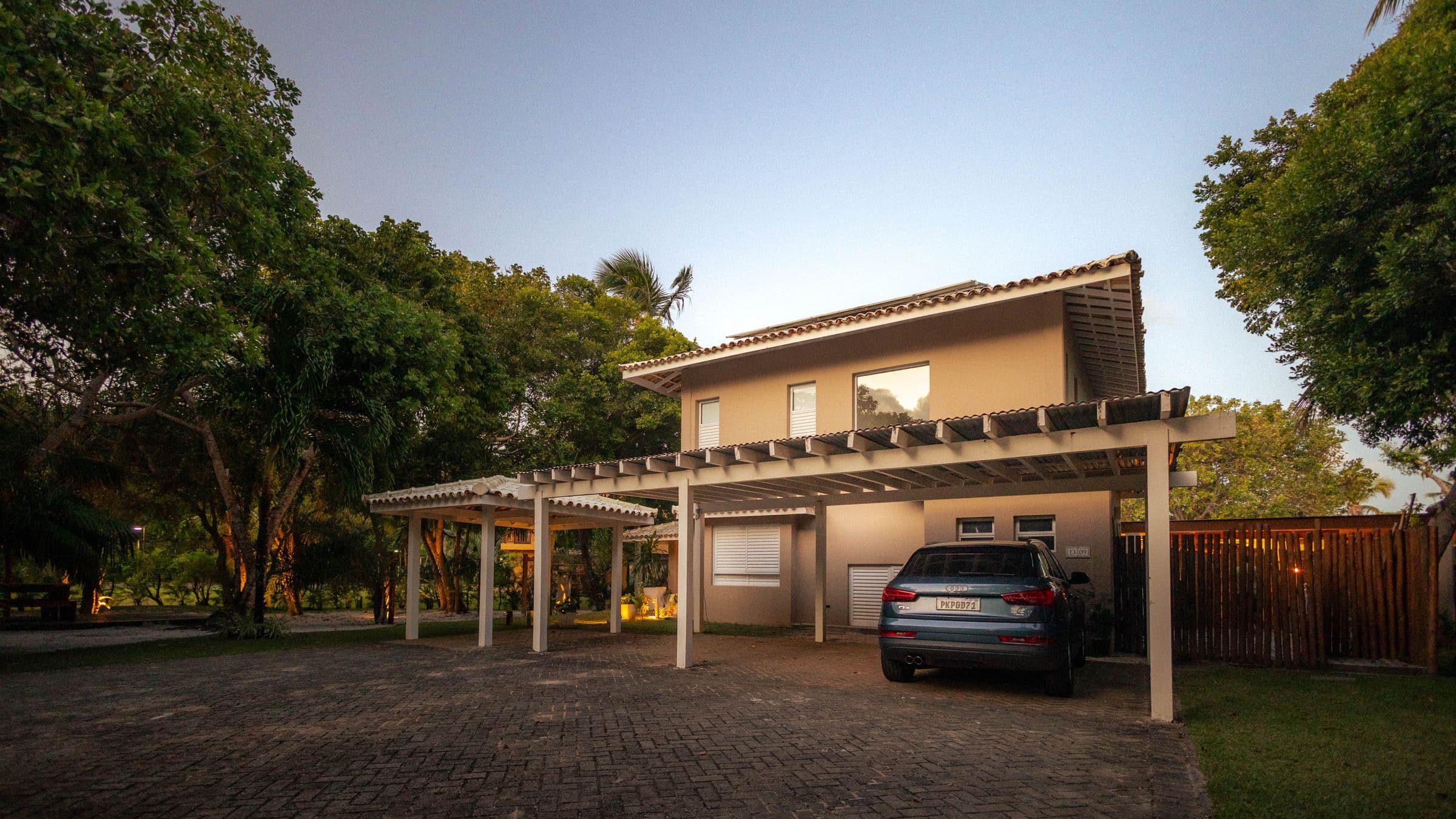 Modern tropical home with warm wood facade and pool at dusk